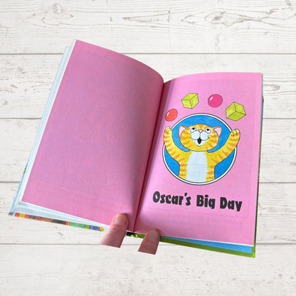 Open book with a pink page featuring a cartoon cat and 'Oscar's Big Day' text on a wooden surface.