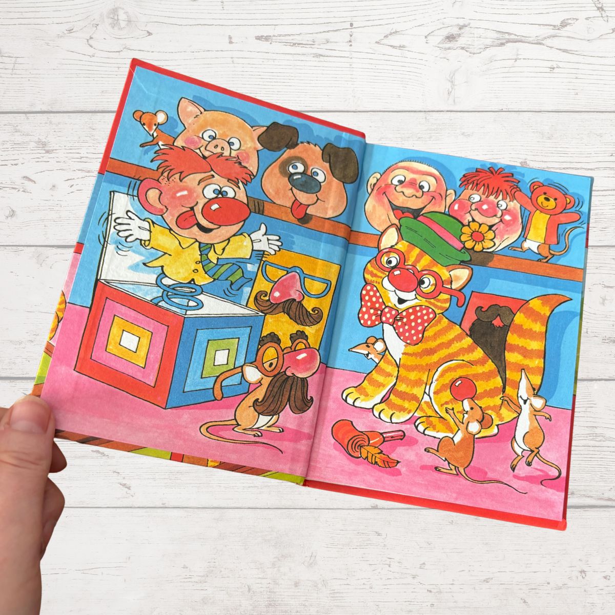 Colorful children's book open to a page with cartoon animals on a wooden surface
