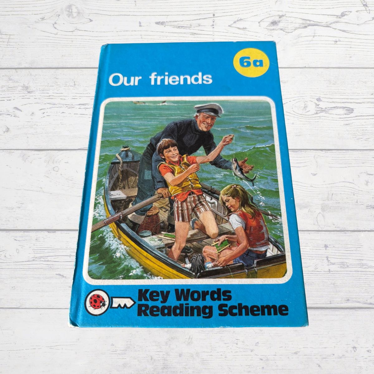 Book cover of 'Our friends' from Key Words Reading Scheme on a wooden surface