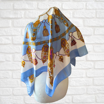 Decorative scarf with intricate patterns on a mannequin against a white brick wall background