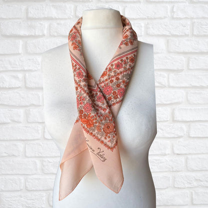 Floral patterned scarf on a mannequin against a white brick wall background