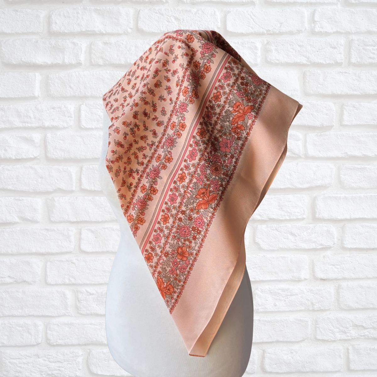 Floral patterned headscarf on a white mannequin against a white brick wall background