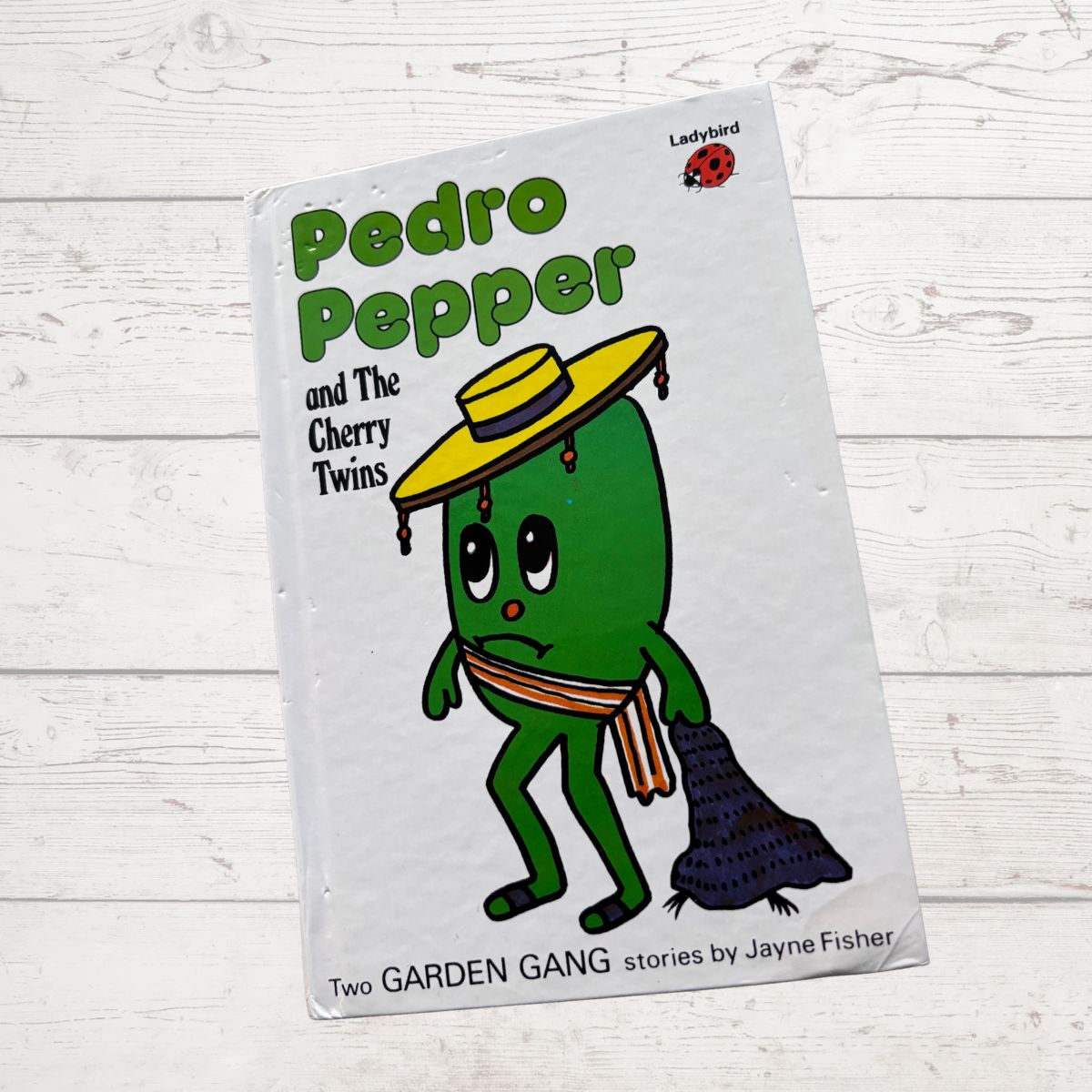 Book cover of 'Pedro Pepper and The Cherry Twins' on a wooden surface