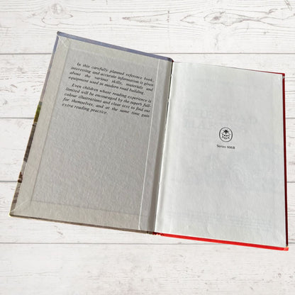 Open book with text and a logo on a light wooden surface