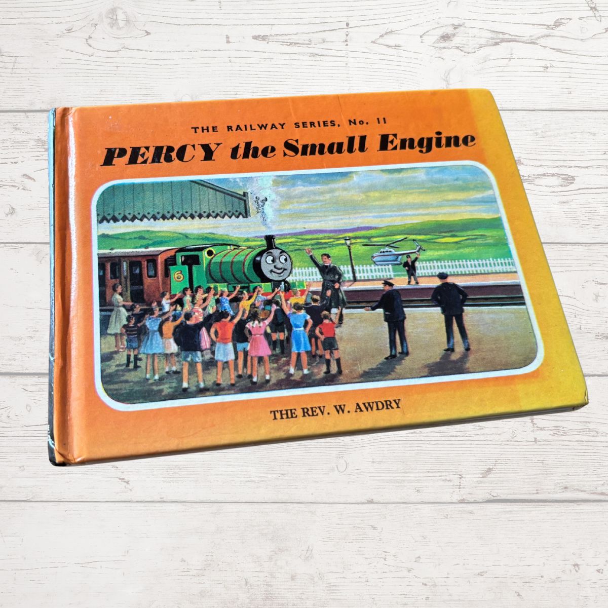Book cover of 'Percy the Small Engine' by W. Awdry on a wooden surface