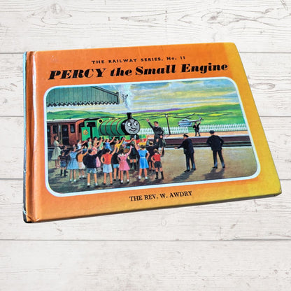 Book cover of 'Percy the Small Engine' by W. Awdry on a wooden surface