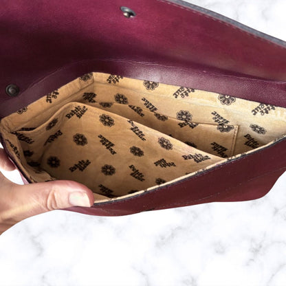 Close-up of a maroon handbag with a beige interior featuring a pattern.