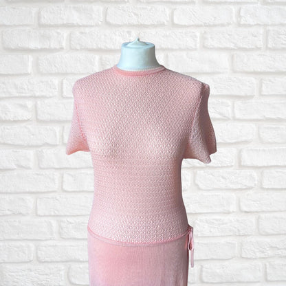 A light pink short-sleeve dress displayed on a mannequin torso against a white brick wall background.