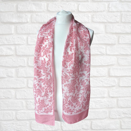 Pink and white patterned scarf on a mannequin against a white brick wall.
