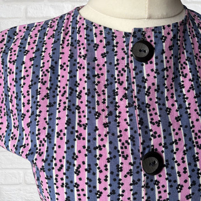 Mannequin wearing a dress  with a purple and pink striped pattern and black buttons.