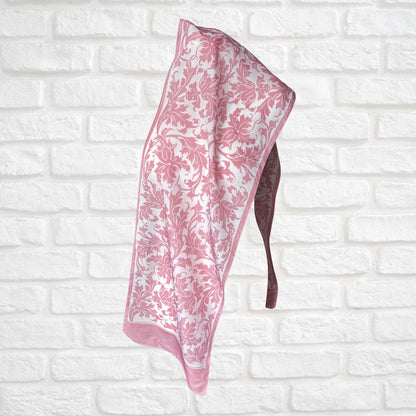 Pink floral-patterned towel on a white brick wall background
