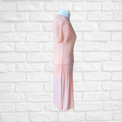 A light pink knitted dress  on a light blue mannequin torso against a white brick wall background 