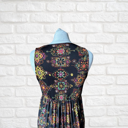 Dress with colorful geometric pattern on a mannequin against a white brick wall.