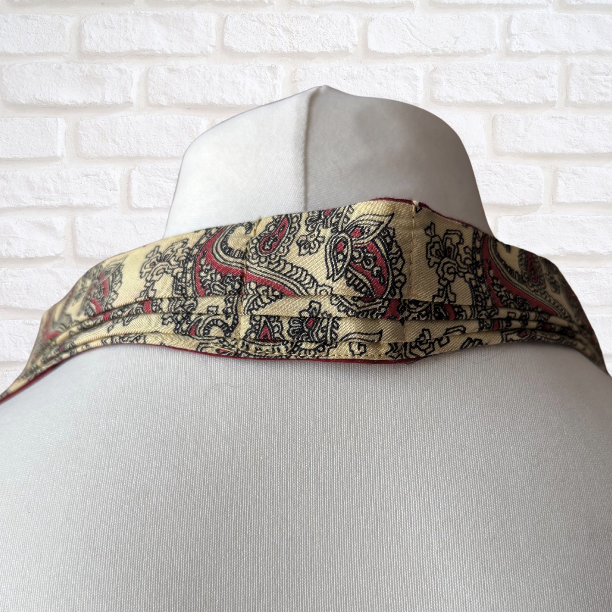 Mannequin wearing a patterned scarf with a white brick wall background