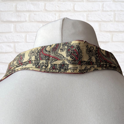 Mannequin wearing a patterned scarf with a white brick wall background