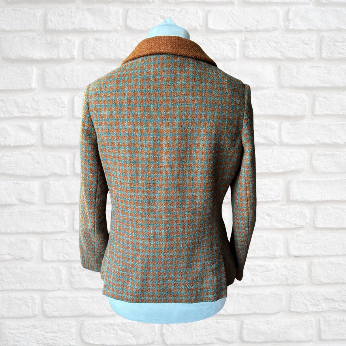 Plaid blazer on a mannequin against a white brick wall background