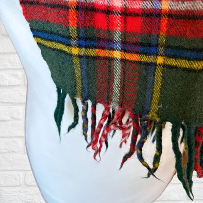 Plaid scarf with fringes draped over a white surface