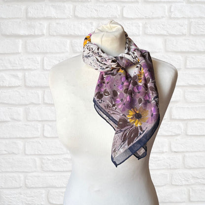 Floral patterned scarf on a mannequin against a white brick wall background