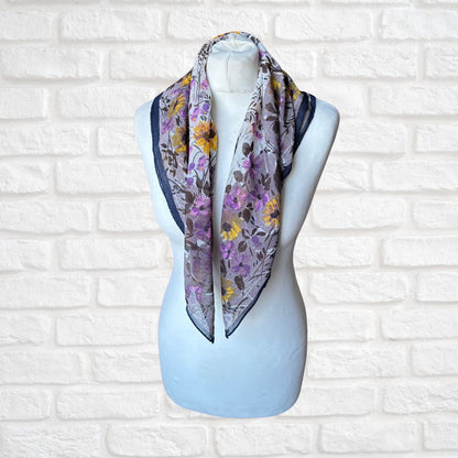 Floral patterned scarf on a mannequin against a white brick wall background