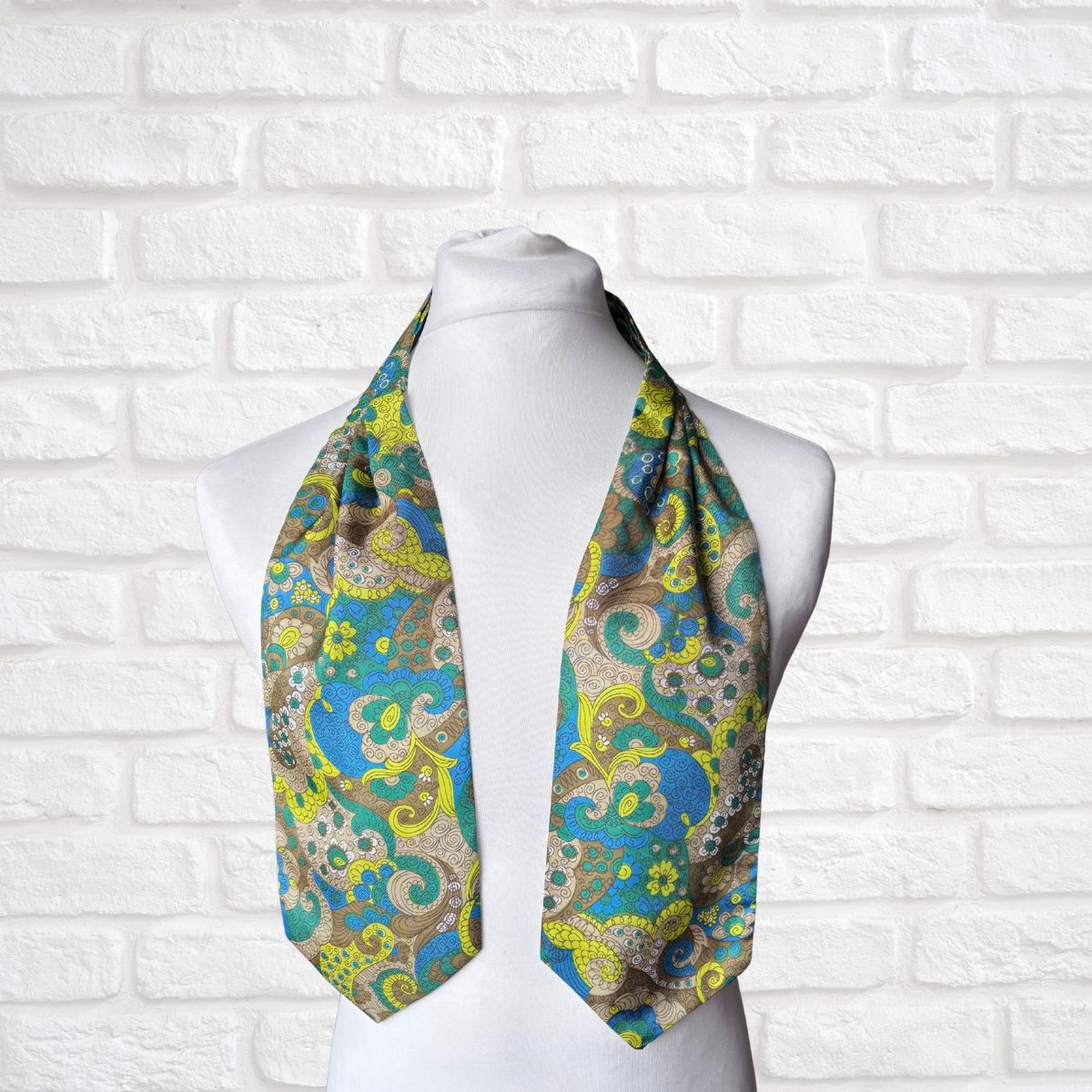 Colorful paisley scarf on a mannequin against a white brick wall background