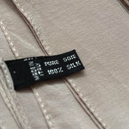 Fabric tag on a beige fabric background with text 'PURE SILK' and '100% SILK'.