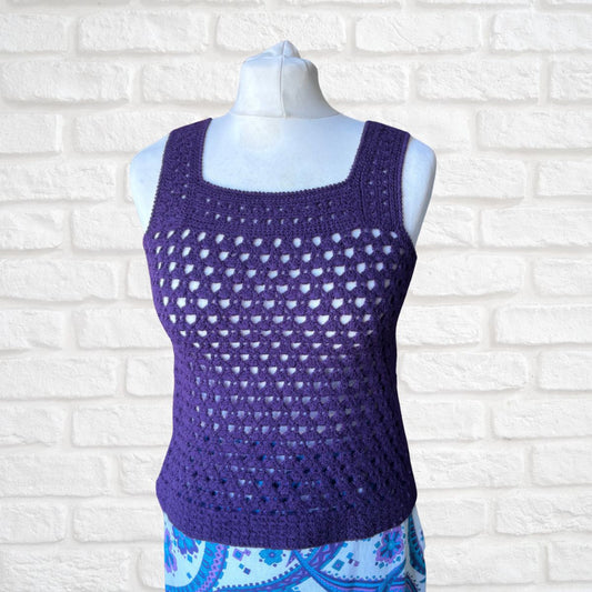 Purple crochet tank top on a mannequin against a white brick wall background