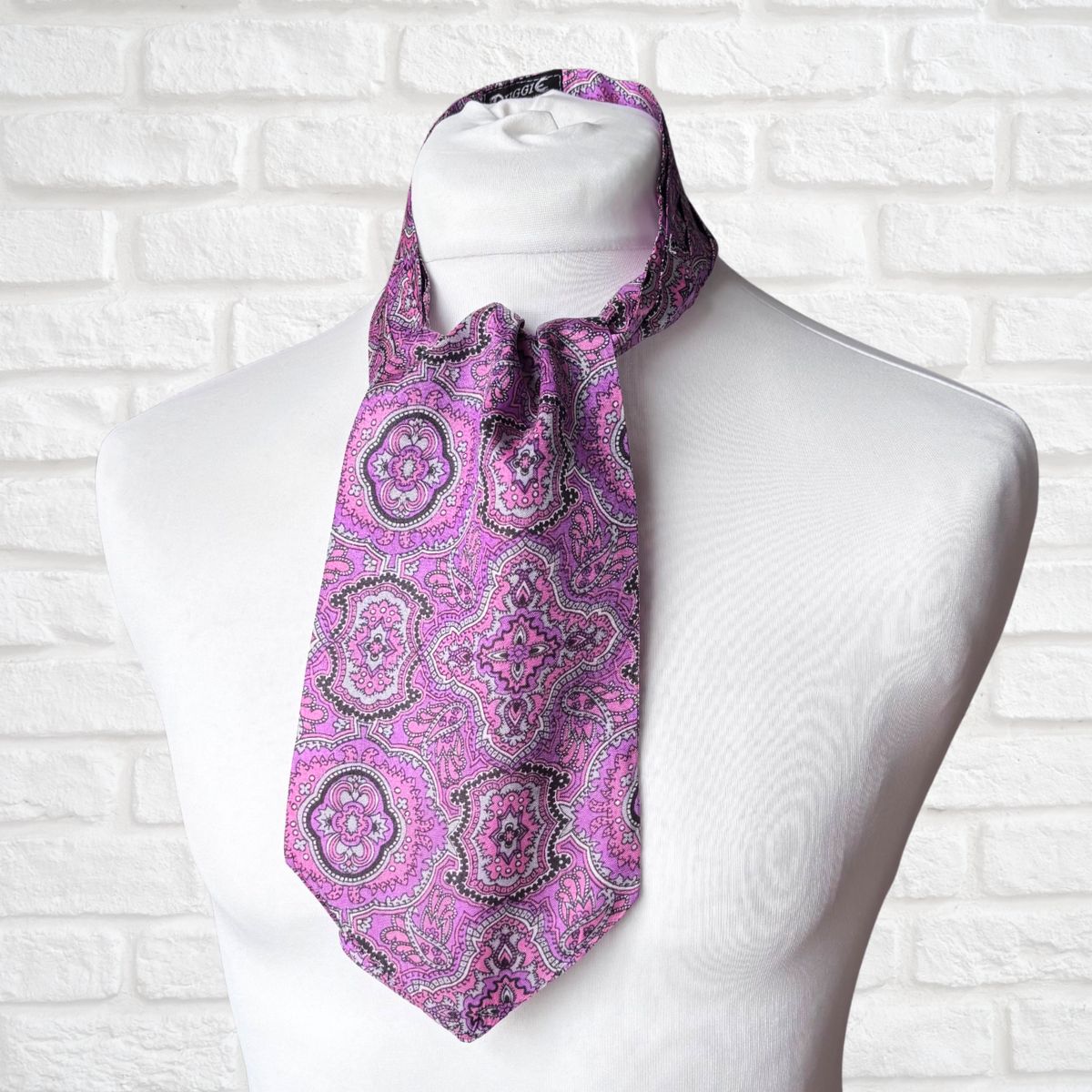 Purple paisley scarf on a mannequin against a white brick wall background