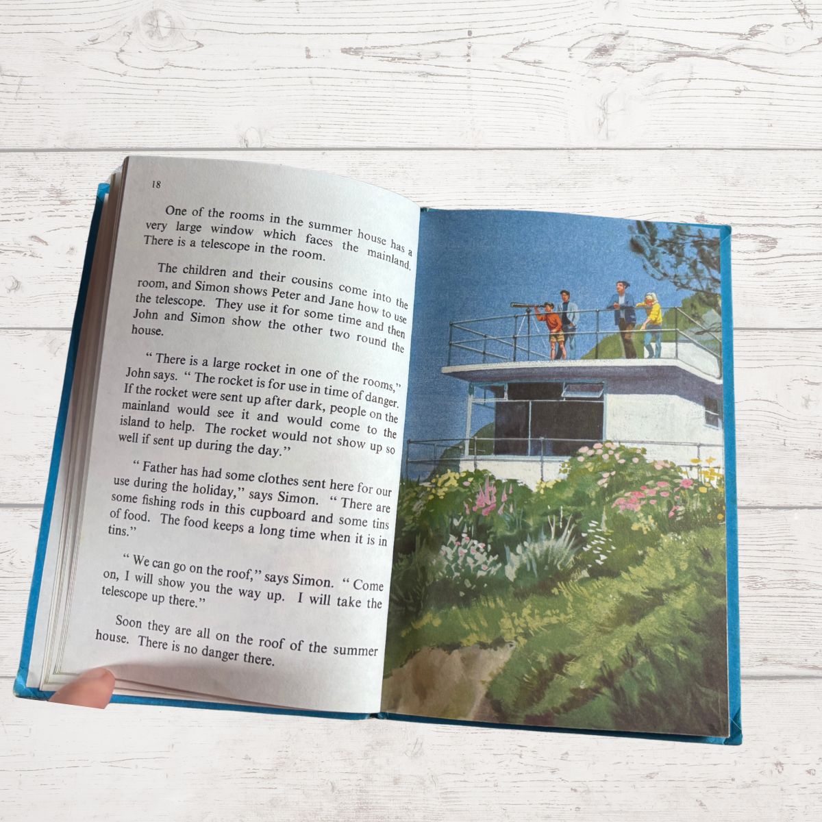 Open book showing a scene with people on a lighthouse and text.