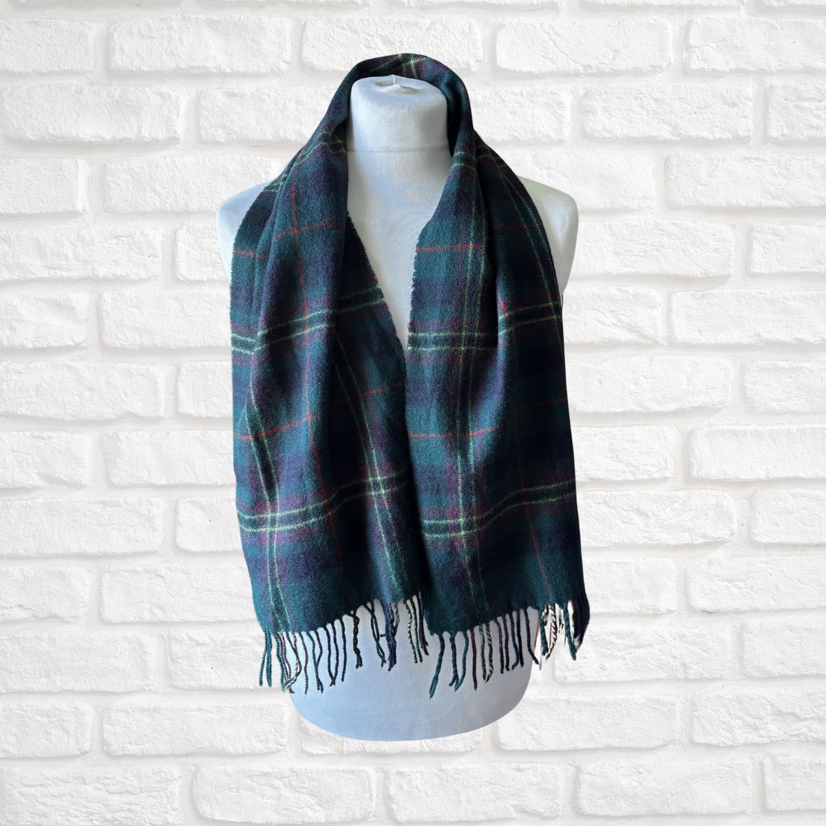 Plaid scarf on a mannequin against a white brick wall