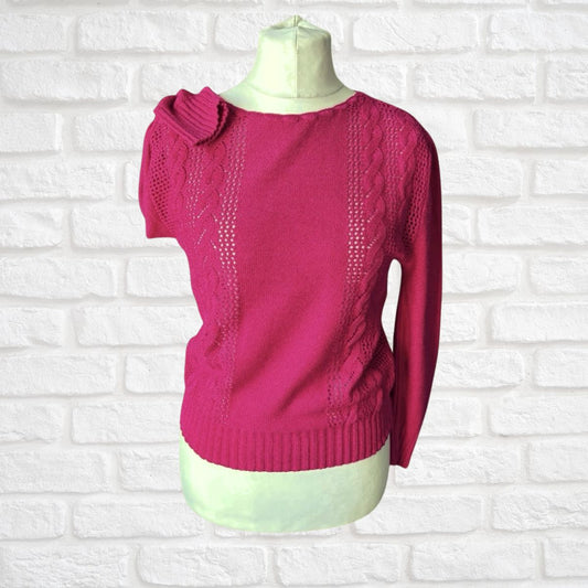 Pink sweater on a mannequin against a white brick wall background