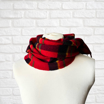 Red and green plaid scarf on a mannequin head against a white brick wall.