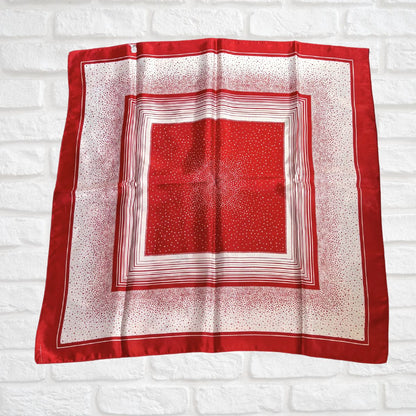 Red and white patterned square scarf on a white brick wall background