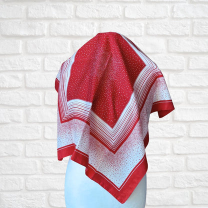Red and white patterned scarf on a mannequin against a white brick wall background