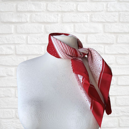 Red and white patterned scarf on a mannequin against a white brick wall background