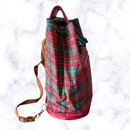 Plaid backpack with a brown strap on a white marble background
