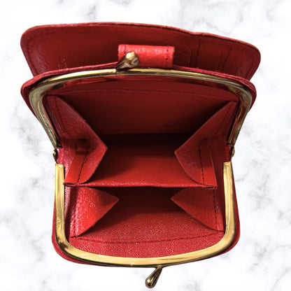 Red leather clutch with gold frame on a white marble background