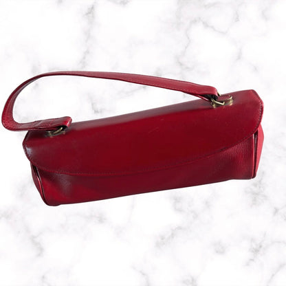 A red leather handbag with a top handle, displayed on a white marble background.