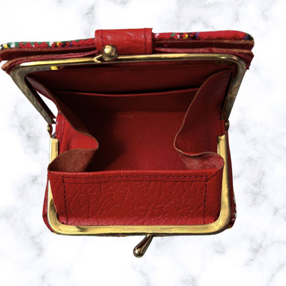 Red leather coin purse with gold frame on a white marble background