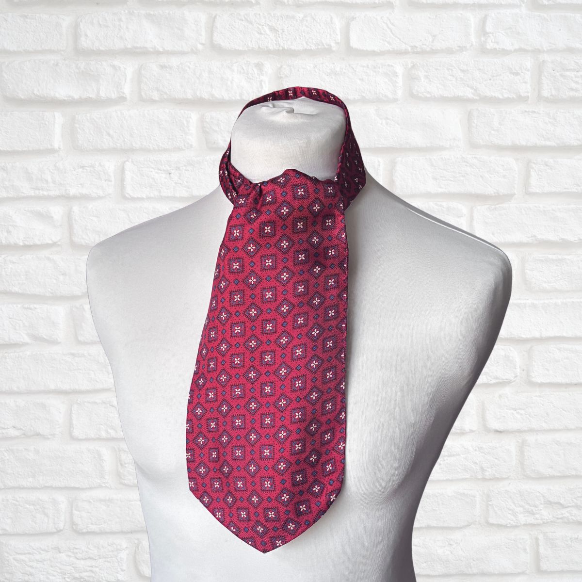 Dark red  patterned necktie on a mannequin against a white brick wall background