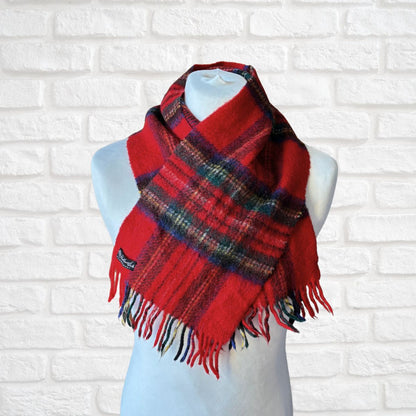 Red plaid scarf on a mannequin against a white brick wall background