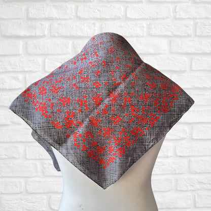 Gray wrap with red floral pattern on a mannequin against a white brick wall.