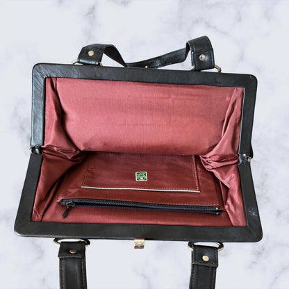 Black leather bag with red interior on a white marble background
