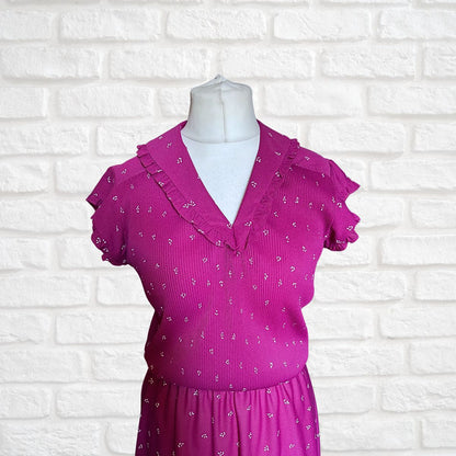 Pink dress with ruffled collar on a mannequin against a white brick wall background