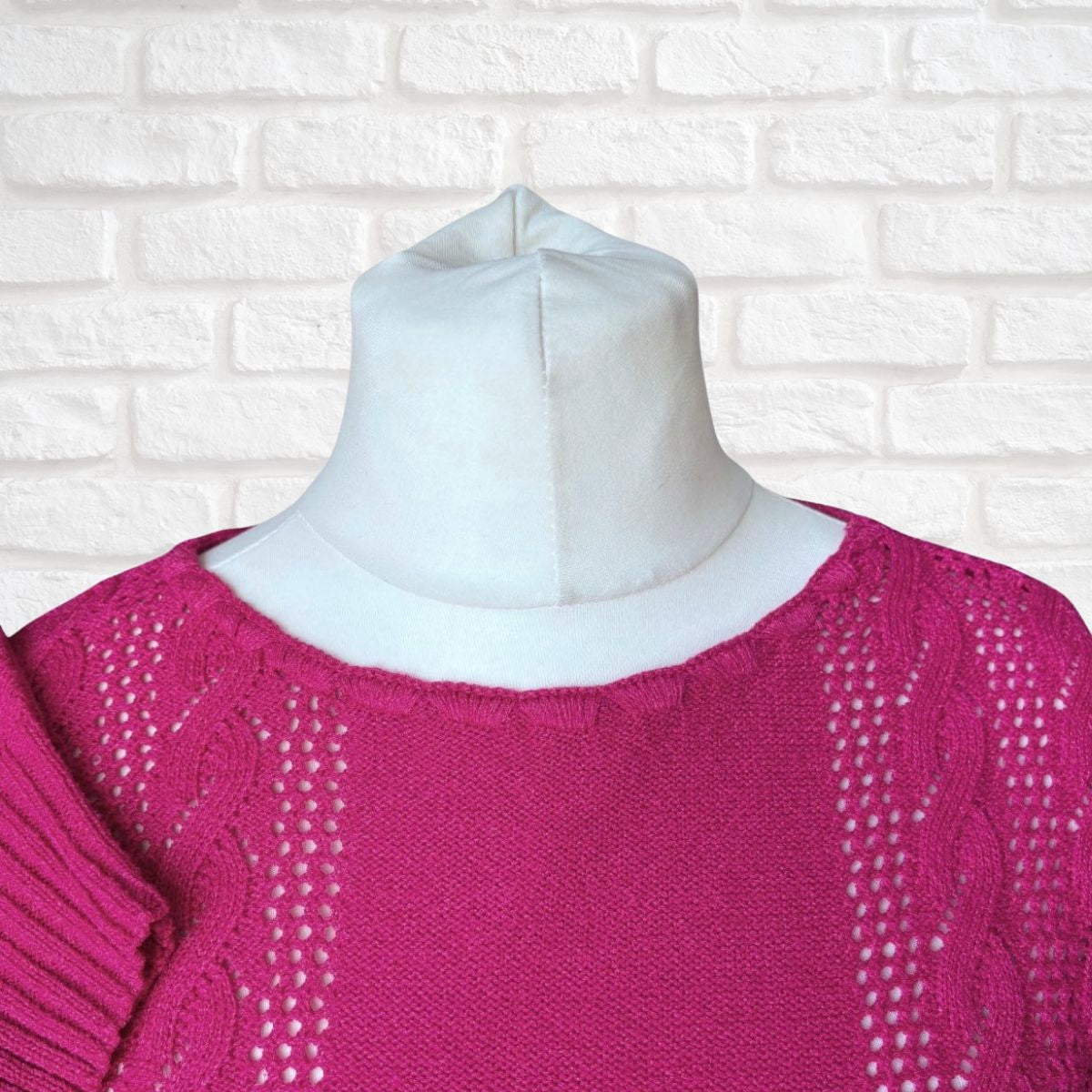 Pink sweater on a mannequin against a white brick wall background