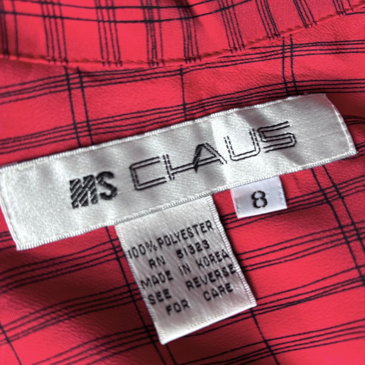 Close-up of a red and black plaid garment interior showing a white sewn-in label for Chaus and a size tag marked 8.