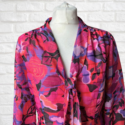 Colorful floral-patterned scarf on a mannequin against a white brick wall.