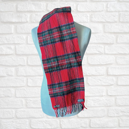 Red plaid scarf on a mannequin against a white brick wall.