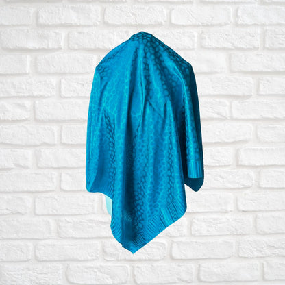 Blue scarf  draped over a chair against a white brick wall.