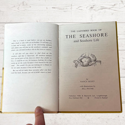Open book titled 'The Ladybird Book of The Seashore and Seashore Life' on a wooden surface.