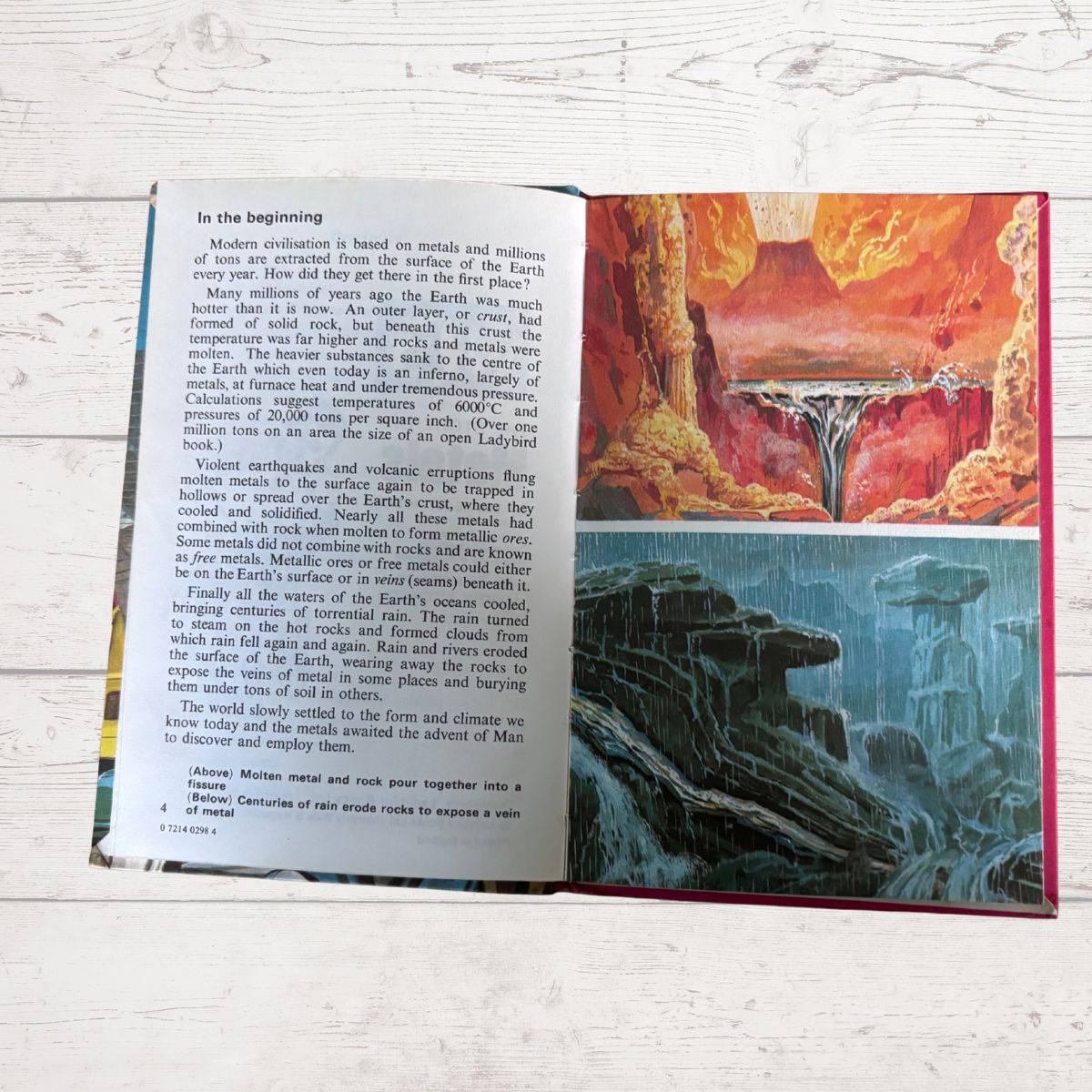 An open book showing printed text on the left page and a colorful illustration of a waterfall on the right page, placed on a light wood surface.